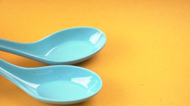 Sarı arka plandaki mutfak aletleri için mavi kaşıkların yakın plan görüntüsü.           