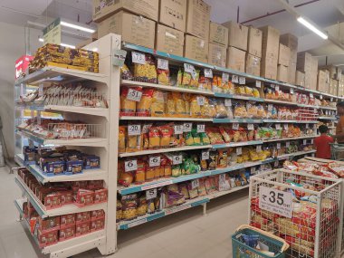Pune, Maharashtra, Hindistan - 13 Ocak 2025; çok çeşitli gıda ürünleriyle dolu hareketli bir market koridoru. Süpermarketteki raflar satılmak üzere renkli paketlerle dolu..