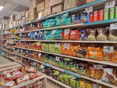 Pune, Maharashtra, Hindistan - 13 Ocak 2025; çok çeşitli gıda ürünleriyle dolu hareketli bir market koridoru. Süpermarketteki raflar satılmak üzere renkli paketlerle dolu..