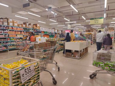 Pune, Maharashtra, Hindistan - 13 Ocak 2025; çok çeşitli gıda ürünleriyle dolu hareketli bir market koridoru. Süpermarketteki raflar satılmak üzere renkli paketlerle dolu..