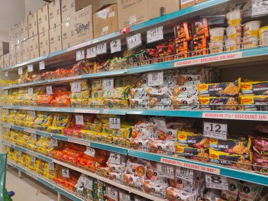 Pune, Maharashtra, Hindistan - 13 Ocak 2025; çok çeşitli gıda ürünleriyle dolu hareketli bir market koridoru. Süpermarketteki raflar satılmak üzere renkli paketlerle dolu..