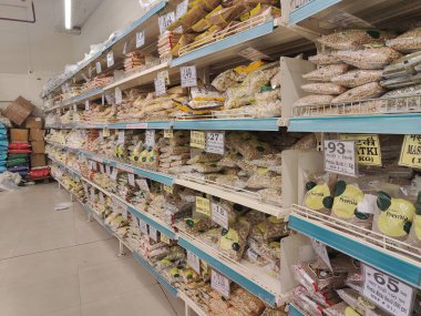 Pune, Maharashtra, Hindistan - 13 Ocak 2025; çok çeşitli gıda ürünleriyle dolu hareketli bir market koridoru. Süpermarketteki raflar satılmak üzere renkli paketlerle dolu..