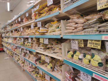 Pune, Maharashtra, Hindistan - 13 Ocak 2025; çok çeşitli gıda ürünleriyle dolu hareketli bir market koridoru. Süpermarketteki raflar satılmak üzere renkli paketlerle dolu..