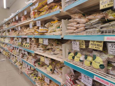 Pune, Maharashtra, Hindistan - 13 Ocak 2025; çok çeşitli gıda ürünleriyle dolu hareketli bir market koridoru. Süpermarketteki raflar satılmak üzere renkli paketlerle dolu..