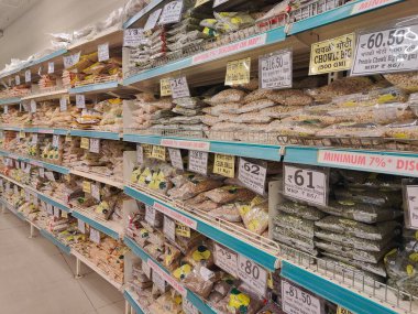 Pune, Maharashtra, Hindistan - 13 Ocak 2025; çok çeşitli gıda ürünleriyle dolu hareketli bir market koridoru. Süpermarketteki raflar satılmak üzere renkli paketlerle dolu..