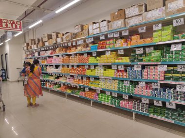 Pune, Maharashtra, Hindistan - 13 Ocak 2025; çok çeşitli gıda ürünleriyle dolu hareketli bir market koridoru. Süpermarketteki raflar satılmak üzere renkli paketlerle dolu..
