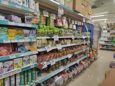 Pune, Maharashtra, Hindistan - 13 Ocak 2025; çok çeşitli gıda ürünleriyle dolu hareketli bir market koridoru. Süpermarketteki raflar satılmak üzere renkli paketlerle dolu..