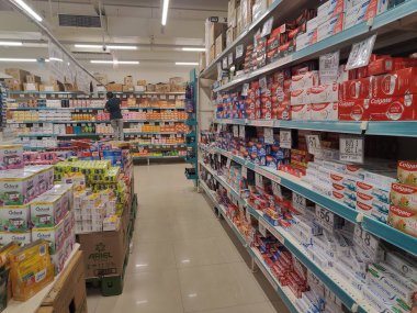 Pune, Maharashtra, Hindistan - 13 Ocak 2025; çok çeşitli gıda ürünleriyle dolu hareketli bir market koridoru. Süpermarketteki raflar satılmak üzere renkli paketlerle dolu..