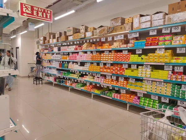Pune, Maharashtra, Hindistan - 13 Ocak 2025; çok çeşitli gıda ürünleriyle dolu hareketli bir market koridoru. Süpermarketteki raflar satılmak üzere renkli paketlerle dolu..