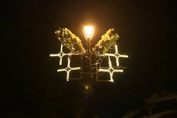 Noel süsleriyle süslenmiş sokak lambası sarı ışıkla parıldıyor..