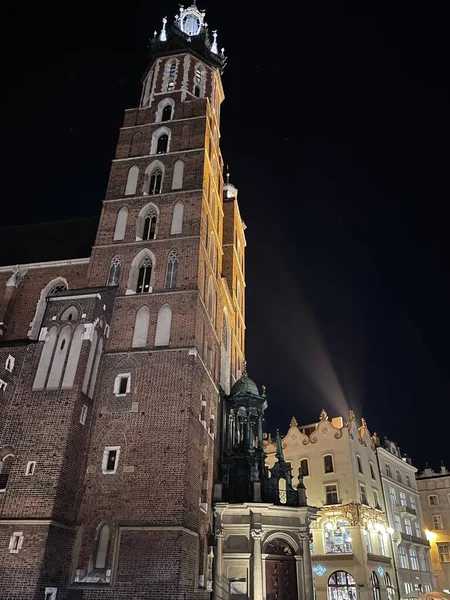 Geceleri Krakow 'daki St. Mary Kilisesi, uzaklarda bir ışık parıltısı.