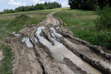 Üzerinde çok su olan çamurlu bir yol. Su bulanık ve yol çamurla dolu.