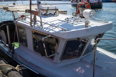 Beyaz bir üst ve siyah bir kıçı olan bir tekne. Tekne bir marinada park halinde.