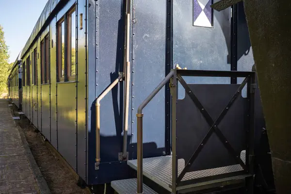 Siyah kapısı ve beyaz işareti olan mavi bir tren vagonu. Tren vagonu raylara park edilmiş.