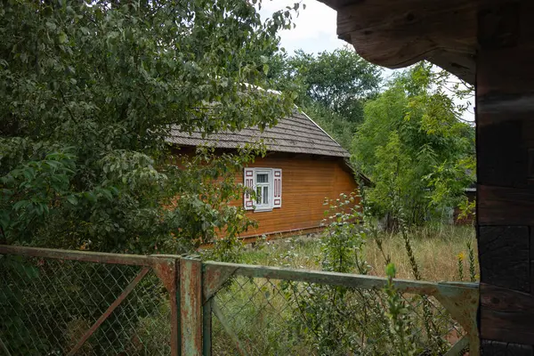 Beyaz pencereli küçük bir ev bir tarlada oturur. Ev ağaçlarla çevrili ve etrafında bir çit var.