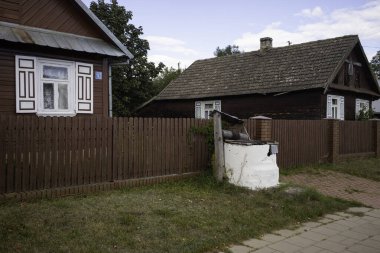 Beyaz çitleri ve beyaz posta kutusu olan küçük bir ev. Çit ahşaptan yapılmıştır ve kahverengi renklidir.