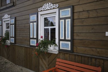 Mavi beyaz panjurlu ve kırmızı banklı ahşap bir bina. Panjurlar çiçeklerle süslenmiş ve tezgah kırmızı.