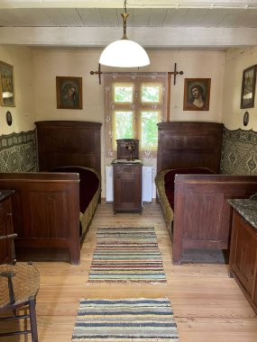 İki yataklı ve masalı küçük bir oda. Oda resimler ve bir lambayla süslenmiş.