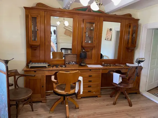 Ahşap bir masa, sandalyeler ve masanın üstünde bir ayna olan bir oda. Odanın kendine has bir havası var.