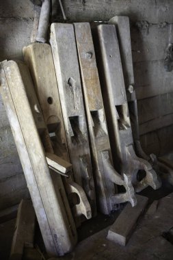 Bir testere ve uçak da dahil olmak üzere bir yığın eski ahşap alet bir duvara dayanıyor.