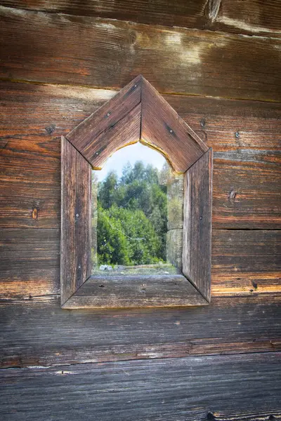 Ağaç manzaralı ahşap bir pencere ve camdaki ağaçların yansıması. Seyircinin pencereden doğanın güzelliğini görebildiği gibi manzara sakin ve sakin. Dışarıdaki ağaçlar gür.