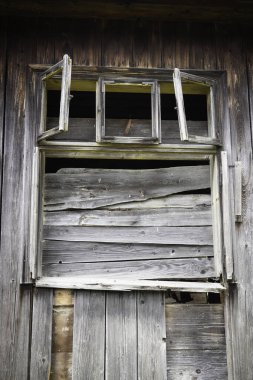 Ahşap bir binada bir pencere açık. Pencere kırılmış ve çerçeve kayıp. Sahne çürüme ve terk edilmedir.