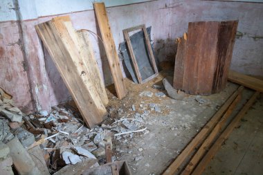 Ahşap döküntüleri ve kırık camlı bir oda. Sahne kargaşa ve yıkımdan ibarettir.