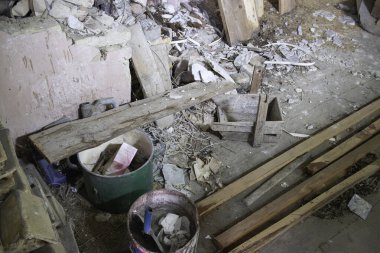 Yeşil kovalı ve mavi kovalı bir odun ve enkaz yığını. Sahne kaotik ve dağınık.