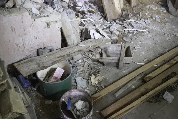 Yeşil kovalı ve mavi kovalı bir odun ve enkaz yığını. Sahne kaotik ve dağınık.