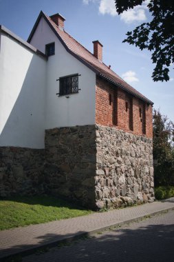 A brick building with a white roof and a window. The building is old and has a rustic appearance