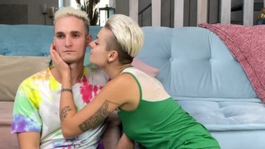 İçerideki şık beyaz çiftin portresi. Kısa saçlı, havalı erkek arkadaşını yanağından öpen genç bir kadın. Oturma odasında kanepenin yanında oturuyor. İlişki, şefkat, bağlanma, aşk konsepti