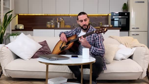 充满热情的中年大胡子男人在屋里弹吉他 有业余爱好的有才华的男人 在家弹奏乐器 他靠自己的力量在客厅里玩音乐来打发业余时间 — 图库视频影像