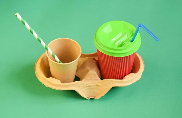 Plastic vs sustainable dinnerware choice. Eco-friendly disposable utensils vs plastic coffee tea cup with drinking straw on green background. Sustainable lifestyle concept.