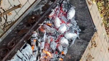 Sıcak kömürde fırında patates pişirmek. Piknikteki şenlik ateşinde folyonun içinde lezzetli sebzeler gömülüydü. Dışarıda vejetaryen yemeği. Kızarmış patatesler ateşte, barbekü. Ormanda yemek, akşam yemeği.