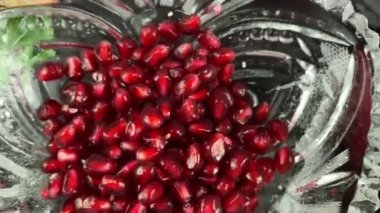Masanın üstünde kırmızı şarap ya da meyve suyu, olgun nar, elma, siyah arka planda yeşil yapraklar. Taze nar arterlerini yakın çekim. Açık meyve tohumları, kapalı alanda dağıtılmış tohumlar. Stüdyo hareketli çekim