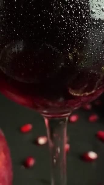 赤ワインやジュース 熟したザクロ リンゴ 黒の背景に緑の葉の組成ガラス クローズアップ新鮮なザクロのアール 開いた果実散乱穀物種子を屋内に切ります — ストック動画