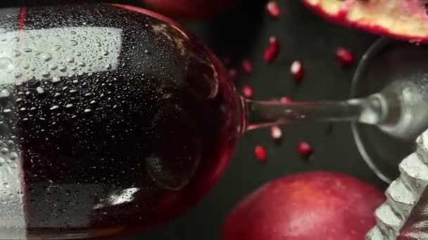 赤ワインやジュース 熟したザクロ リンゴ 黒の背景に緑の葉の組成ガラス クローズアップ新鮮なザクロのアール 開いた果実散乱穀物種子を屋内に切ります — ストック動画