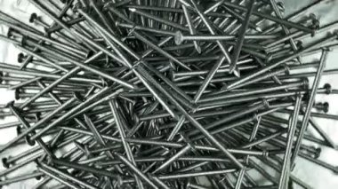 Stüdyo ışıklarında gümüş folyoda dönen çelik çivi yığınının tam üstünde. İnşaat alanı için metal donanım. Keskin detaylar. Metalik tamir malzemesi. Galvanize raptiyeler marangoz