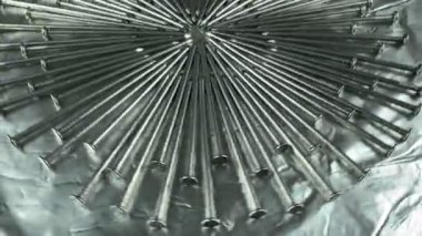 Stüdyo ışıklarında gümüş folyo üzerinde dönen tek renkli çelik çiviler. İnşaat alanı için metal donanım ayarlandı. Demir keskinliği endüstriyel çalışmaları açıklar. Metalik tamir malzemesi. Galvanize raptiyeler marangoz