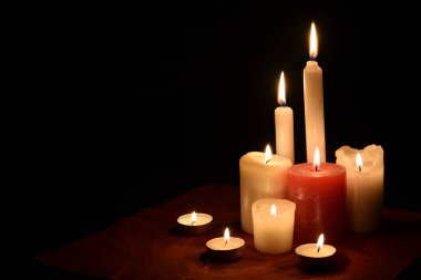 Burning candles on table on black background indoors. Concept of mourn, grief or mourning. Memorial Day. Copy space