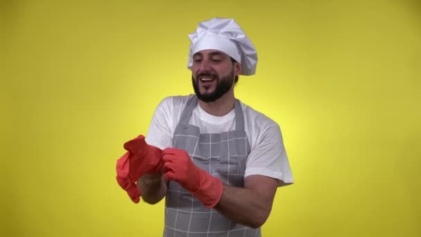 快乐的大厨做饭后准备好了清洁 戴着被黄色背景隔开的洗碗手套 热心的男性厨师热爱他的工作 准备食物概念 — 图库视频影像