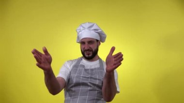 Heyecanlı sakallı aşçı neşeli, sarı arka planda izole edilmiş memnuniyetini dile getiriyor. Neşeli bir adam el kol hareketi yapıyor, şefleri öpüyor, mutluluk deneyimliyor, iyi ruhlar yaşıyor. Yemek pişirme kavramları