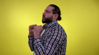 Portre pozitifliği olan sakallı bir adam, gündelik giysiler içinde müziğe doğru hareket ediyor, olumlu gülümsüyor, iyi bir ruh hali içinde, dans ediyor, sarı arka planda soyutlanmış. Neşeli yetişkin adam eğleniyor.
