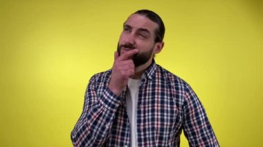 Sıradan giyinmiş yetişkin sakallı bir adamın portresi hatırlamaz. Kafası kaşınır, derin düşünür, sarı arka planda izole bir şekilde yukarı bakar. Yüz ifadesi, duygu, his, vücut işareti kavramı