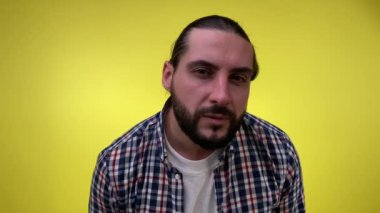 Şaşırmış sakallı adam, sarı arka planda izole edilmiş kameraya yaklaşırken hoş bir sürpriz hissediyor. Mutlu adam gülümsüyor olumlu cevap veriyor evet harika seçim onaylandı iyi fikir