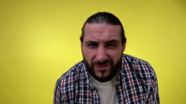 Sakallı orta yaşlı bir adamın portresi, ifadeyle kaşlarını çatarak sırıtıyor, güçlü bir tiksinti, kesinlikle memnun değil, sarı arka plandaki kameraya yakından yaklaşırken algılıyor..