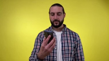 Orta yaşlı sakallı bir adamın portresi yeşil ekran akıllı telefon kroma anahtarının izole edilmiş sarı arka plan gülümsemesini gösteriyor. Uzay reklam konseptini kopyala. Telefon kullanan olumlu bir erkek özel bir teklif sunuyor.