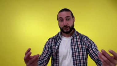 Kızgın, orta yaşlı, sakallı bir adam sarı arka planda izole edilmiş kameraya bakıyor. Portre rahatsız erkek kişi duygusal konuşuyor, bağırarak kınıyor hata veya yanlış diye bağırıyor.