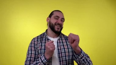 Neşeli olgun adam eğlenmeyi kutluyor. Sıradan kıyafetlerle dans eden yakışıklı sakallı adam, müziğe doğru hareket eden, olumlu gülümseyen, sarı arka planda izole edilmiş iyi bir ruh hali içinde olan..