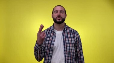 Gözü kapalı sakallı adam, şans diliyor, sarı arka planda parmaklarını çapraz tutuyor. Yetişkin bir erkek hayal kuruyor ve en iyisini bekliyor. Şans konsepti, el hareketi.